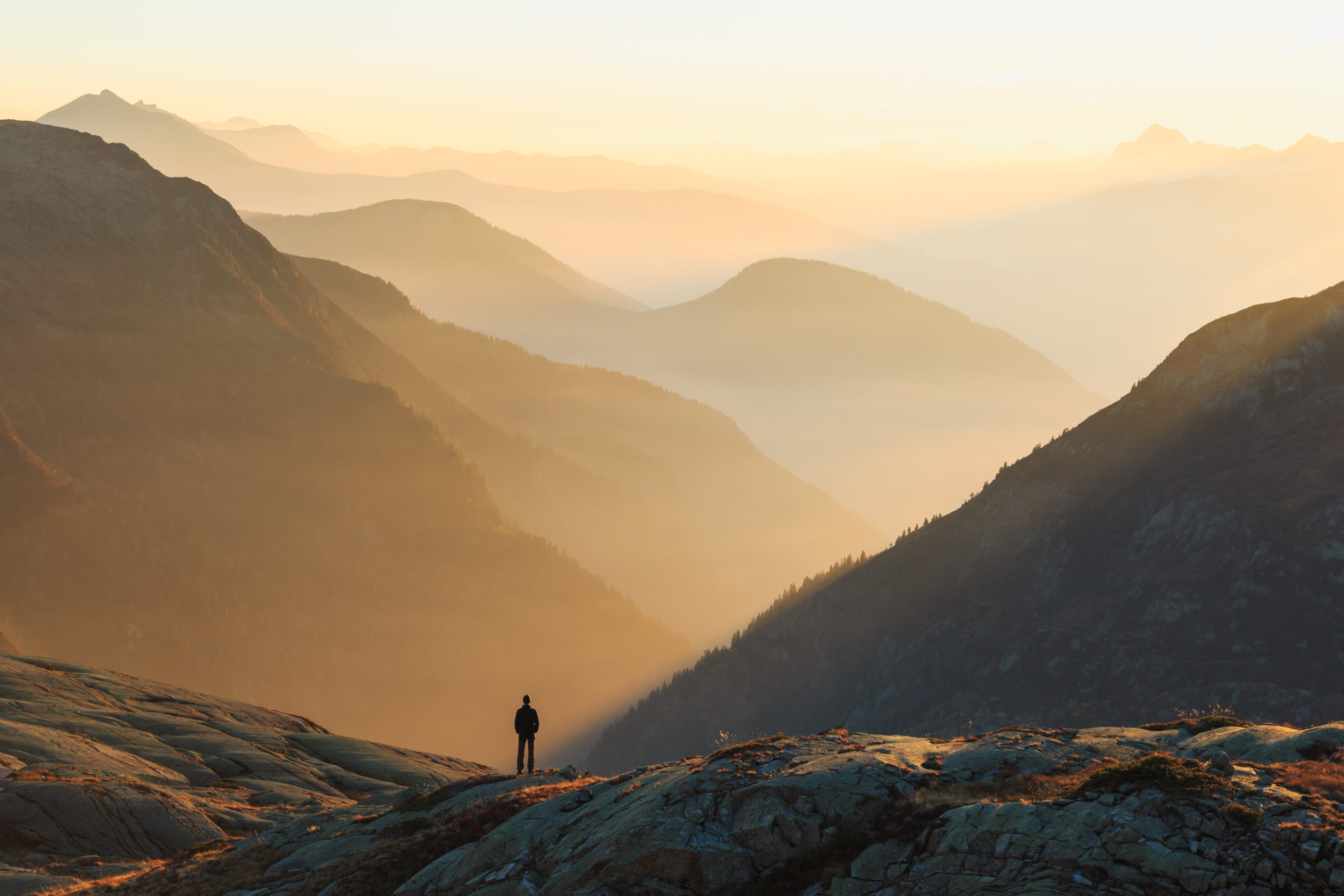 Man looking at the coulorful layers of mountains during sunset. Chamonix, France.